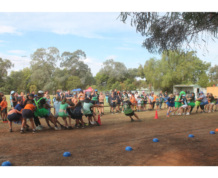 Students and staff competing in a tug-o-war match on the schools sports oval