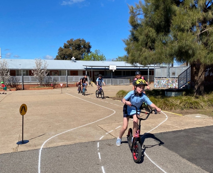 Primary students on scooters and bicycles following our temporary track in the mid school quad